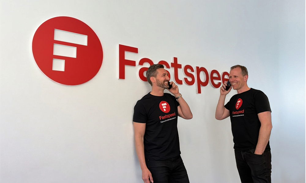 Morten og Jens der taler i telefon foran Fastspeed logo