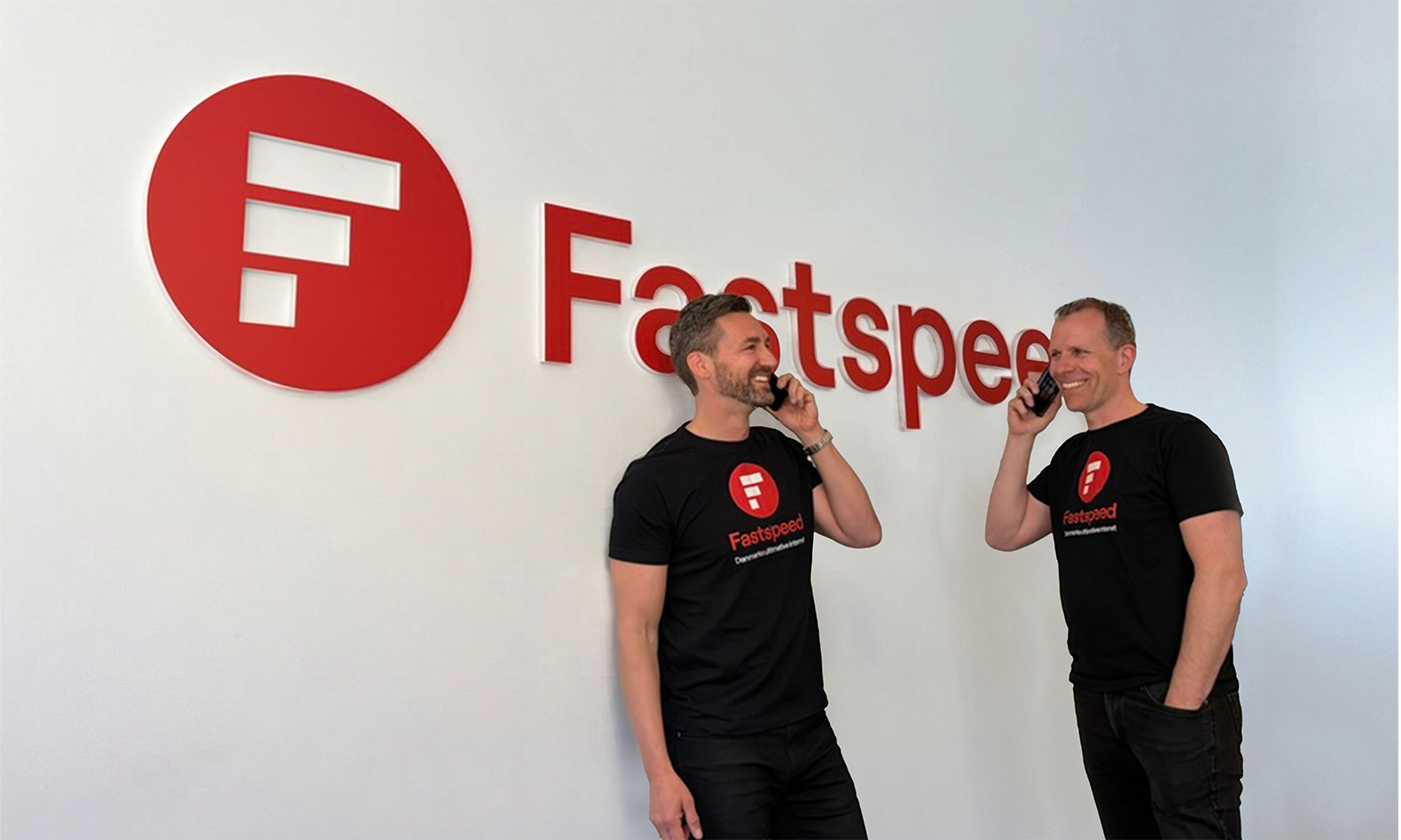 Morten og Jens der taler i telefon foran Fastspeed logo